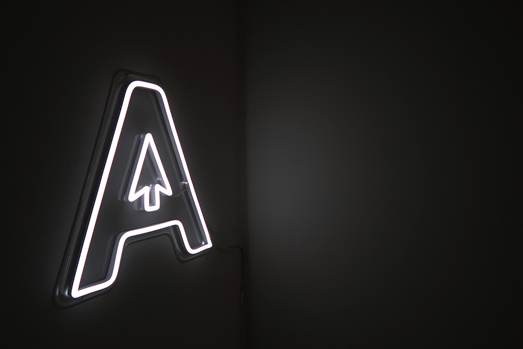 Upper case letter A on a black wall. The letter is light with leds